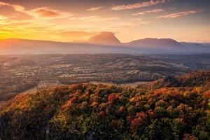 Sunset over mountain range with colorful autumn forest on hill in countryside photo