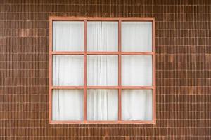 baldosas de arcilla de pared y ventana de madera con cortina blanca de casa tropical foto