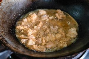 freír carne de pollo frito crujiente con aceite hirviendo en una sartén en una estufa de gas foto