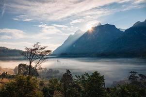 Scenery of sunrise over mountain range with foggy in tropical rainforest at national park photo