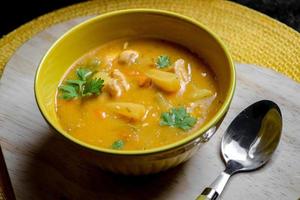 bowl of soup in a wooden with spoon photo