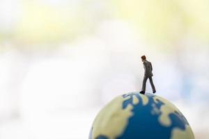 Global Business and Planning Concept. Close up of businessman miniature figure people walking on world mini ball with copy space. photo