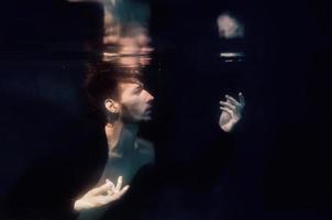 man in a swimming pool underwater on black background photo