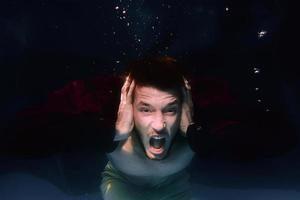 An underwater shot of a man screaming in a swimming pool on black background photo