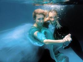 hermosa pareja bailando bajo el agua en la piscina foto