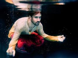 man doing yoga in a swimming pool underwater photo