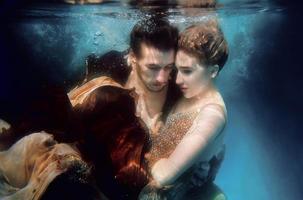 hermosa pareja bailando bajo el agua en la piscina foto