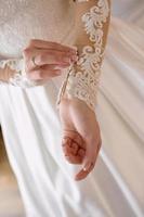 Bride hands closing buttons on her wedding dress. Wedding, love, bride concept photo