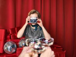 mujer alegre y hermosa fotógrafa en la celebración de la fiesta con fondo de cortinas rojas. profesión, concepto de fiesta foto