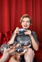 mujer alegre y hermosa fotógrafa en la celebración de la fiesta con fondo de cortinas rojas. profesión, concepto de fiesta foto
