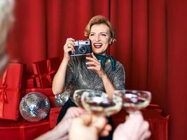 mujer alegre y hermosa fotógrafa en la celebración de la fiesta con fondo de cortinas rojas. profesión, concepto de fiesta foto