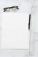 papel de formato a4 con gafas y bolígrafo sobre la mesa foto