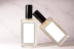 Two glass perfume bottles on white marble background photo