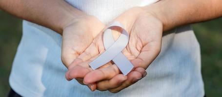 mes de concientización sobre el cáncer cerebral, mano de mujer sosteniendo una cinta de color gris para apoyar a las personas que viven. concepto de salud y día mundial del cáncer