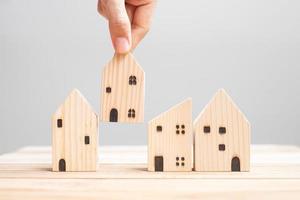 Business man holding wooden house model on table background. Home, Crisis, Economic recession, Homeless, Real Estate, Buy or Rent and Property concept photo