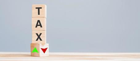 wood cube block with TAX text to UP and Down arrow symbol icon. Financial, Management, Economic, business and time to tax concept photo