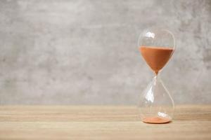 Hourglass on table, Sand flowing through the bulb of Sandglass measuring the passing time. countdown, deadline, Life time and Retirement concept photo