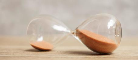 Hourglass on table, Sand flowing through the bulb of Sandglass measuring the passing time. countdown, deadline, Life time and Retirement concept photo