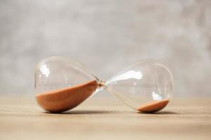 Hourglass on table, Sand flowing through the bulb of Sandglass measuring the passing time. countdown, deadline, Life time and Retirement concept photo