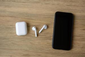 White wireless earphone or headphones on table for using with smartphone. Technology concept photo