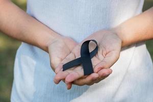 Melanoma and skin cancer, Vaccine injury awareness month and rest in peace concepts. Woman holding black Ribbon photo