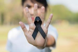 Melanoma and skin cancer, Vaccine injury awareness month and rest in peace concepts. Woman holding black Ribbon photo