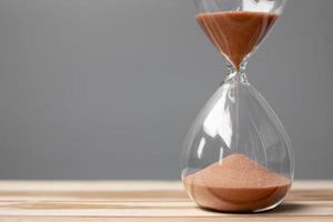 Hourglass on table office with copy space, Sand flowing through the bulb of Sandglass measuring the passing time. countdown, deadline, Life time and Retirement concept photo