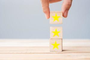 Hand holding wooden blocks with the star symbol. Customer reviews, feedback, rating, ranking and service concept. photo