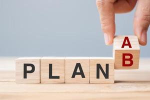 Businessman hand flipping wooden cube blocks with PLAN A change to PLAN B text on table background. strategy, leadership, management, marketing, project and Crisis concepts photo