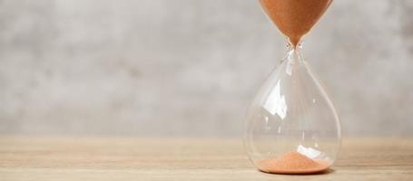 Hourglass on table, Sand flowing through the bulb of Sandglass measuring the passing time. countdown, deadline, Life time and Retirement concept photo