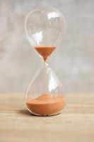 Hourglass on table, Sand flowing through the bulb of Sandglass measuring the passing time. countdown, deadline, Life time and Retirement concept photo