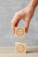 hand holding smile face block. Customer choose Emoticon for user reviews. Service rating, ranking, customer review, satisfaction, mood, mental health and feedback concept photo