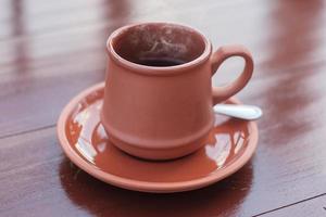 mug of hot coffee or tea on wooden table in the morning with mountain and nature background photo