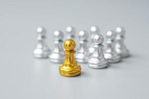 piezas de peón de ajedrez dorado o empresario líder se destacan entre la multitud de hombres plateados. concepto de gestión de liderazgo, negocios, equipo, trabajo en equipo y recursos humanos foto