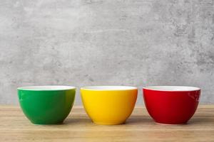 stack of colorful coffee cups on wall background at cafe. Green, yellow and red color ceramic mug on table at home. International coffee day concept photo