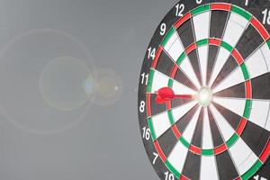 Red dart hitting a target on center of Bullseye or Dartboard. Business, competition, goal, success and marketing concept photo