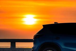 Blue compact SUV car with sport and modern design parked on concrete road by the sea at sunset in the evening. Hybrid and electric car technology concept. Car parking space. Automotive industry. photo