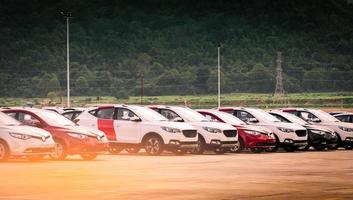 Luxury red and white new suv car parked on concrete parking area at factory near mountain. Car stock for sale. Car factory parking lot. Automotive Industry concept. Car dealership. photo