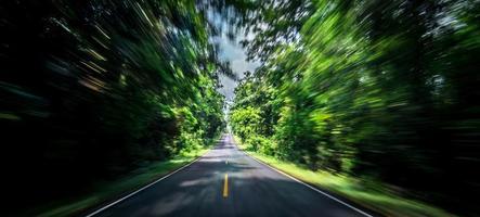 Empty asphalt road and speed motion blur on highway in summer with green trees forest at countryside photo