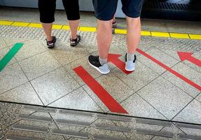 Passenger standing at railway platform waiting for board the high speed electric train at subway station. Modern train transport. Tourist standing at floor paint red arrow sign. Urban travel lifestyle photo