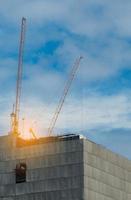 Construction crane on high-rise building with blue sky and white clouds. Construction site of commercial building or condominium or apartment in the city. Real estate business. Architecture background photo