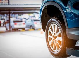 enfoque selectivo en la rueda trasera del coche suv azul sobre fondo borroso. camión con neumático nuevo de alto rendimiento estacionado en el taller de garaje después de cambiar el neumático y el mantenimiento. revise el neumático antes del concepto de viaje. foto