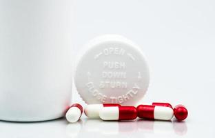 Capsules pills on white background and plastic bottle with blank label and copy space. Childproof packaging. Child resistant pill container. Push down and turn cap. Global healthcare concept. photo