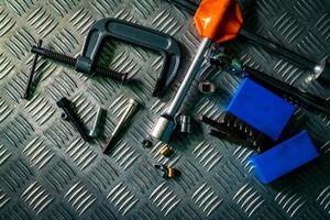 Top view of tools on industrial metal checker plate. Metal checkerplate for anti skid. Nut, bolts, and hex key on metal sheet floor. Silver bump ground with art pattern. Silver texture background. photo