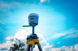 GPS surveying equipment on blue sky and white clouds background. GPS, GIS, and GNSS equipment. Land survey for map. Technology for marks land to made satellite map on the earth. Smart GNSS GPS survey. photo