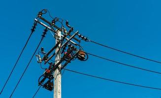 poste eléctrico de alto voltaje y líneas de transmisión con cielo azul claro. torres de electricidad. sistema de ingeniería de potencia y energía. Torre de alto voltaje de peligro. alambre de cable en poste eléctrico. industria de la energía. foto