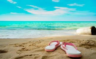 sandalias rosas y blancas en la playa de arena. Las chancletas de estilo casual se quitaron en la playa. vacaciones de verano en la playa tropical. divertido viaje de vacaciones en la playa de arena. Hora de verano. vibras de verano. tiempo de relajación. foto