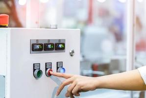 la mano del ingeniero presiona el botón rojo para apagar la máquina de control de temperatura. El gabinete del panel de control de temperatura contiene una pantalla digital para medir la temperatura. Control de calor en fábrica industrial. foto