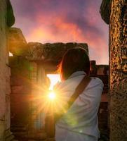 Rearview of woman photographer travel in Phimai Historical Park with sunset sky. Landmark of Nakhon Ratchasima, Thailand. Travel destinations. Historic site is ancient. Ancient building. Khmer temple. photo