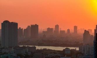 Cityscape with polluted air. Air pollution. Smog and fine dust covered city in the morning with orange sky. Environmental problem in big city. Toxic fine dust. Unhealthy air. Urban unhealthy living. photo